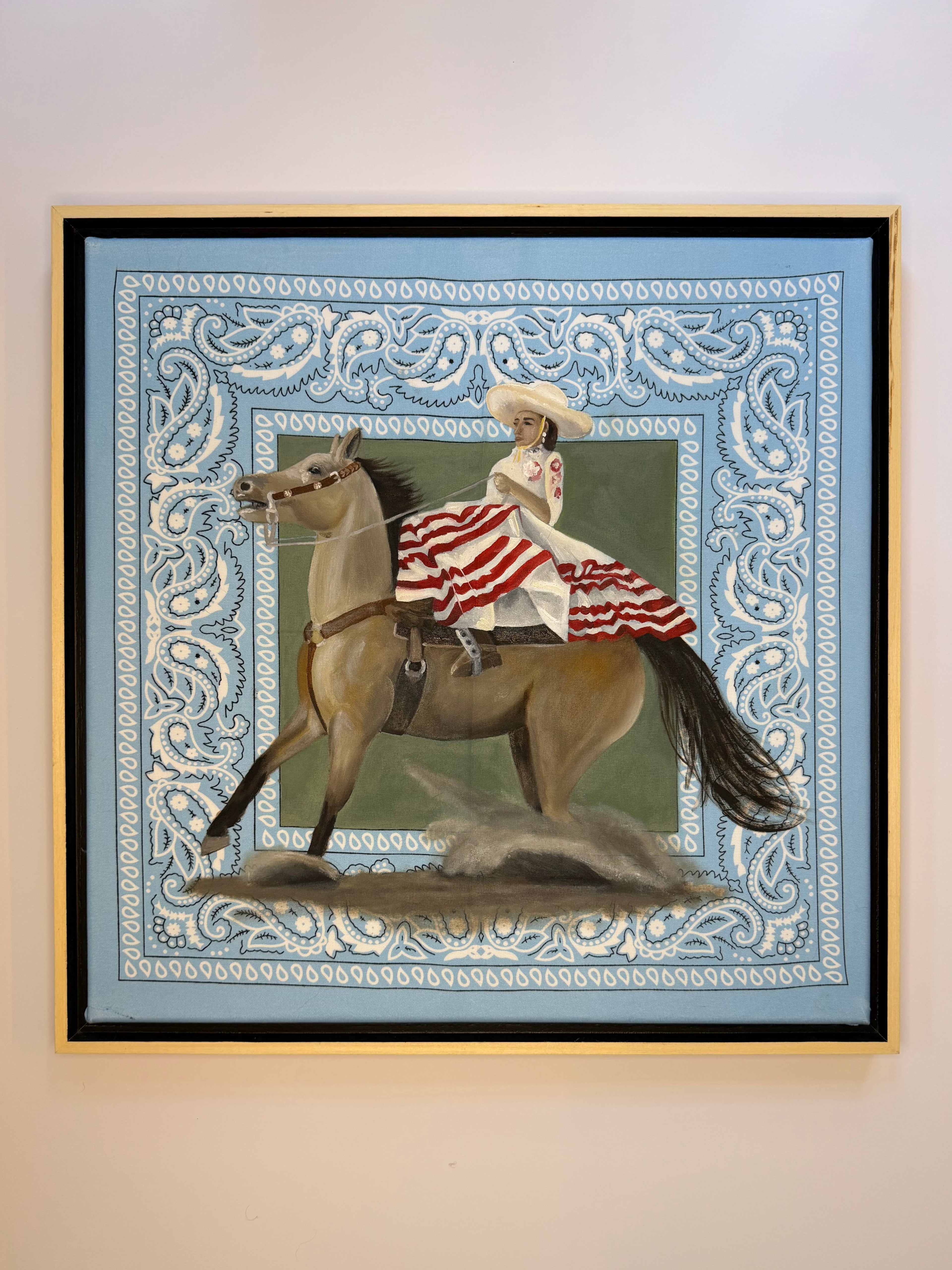 Bandana Series painting, La Escaramuza, by Texas artist Jenny Wagner shown on a white wall in a natural wood floater frame that reveals the canvas edges