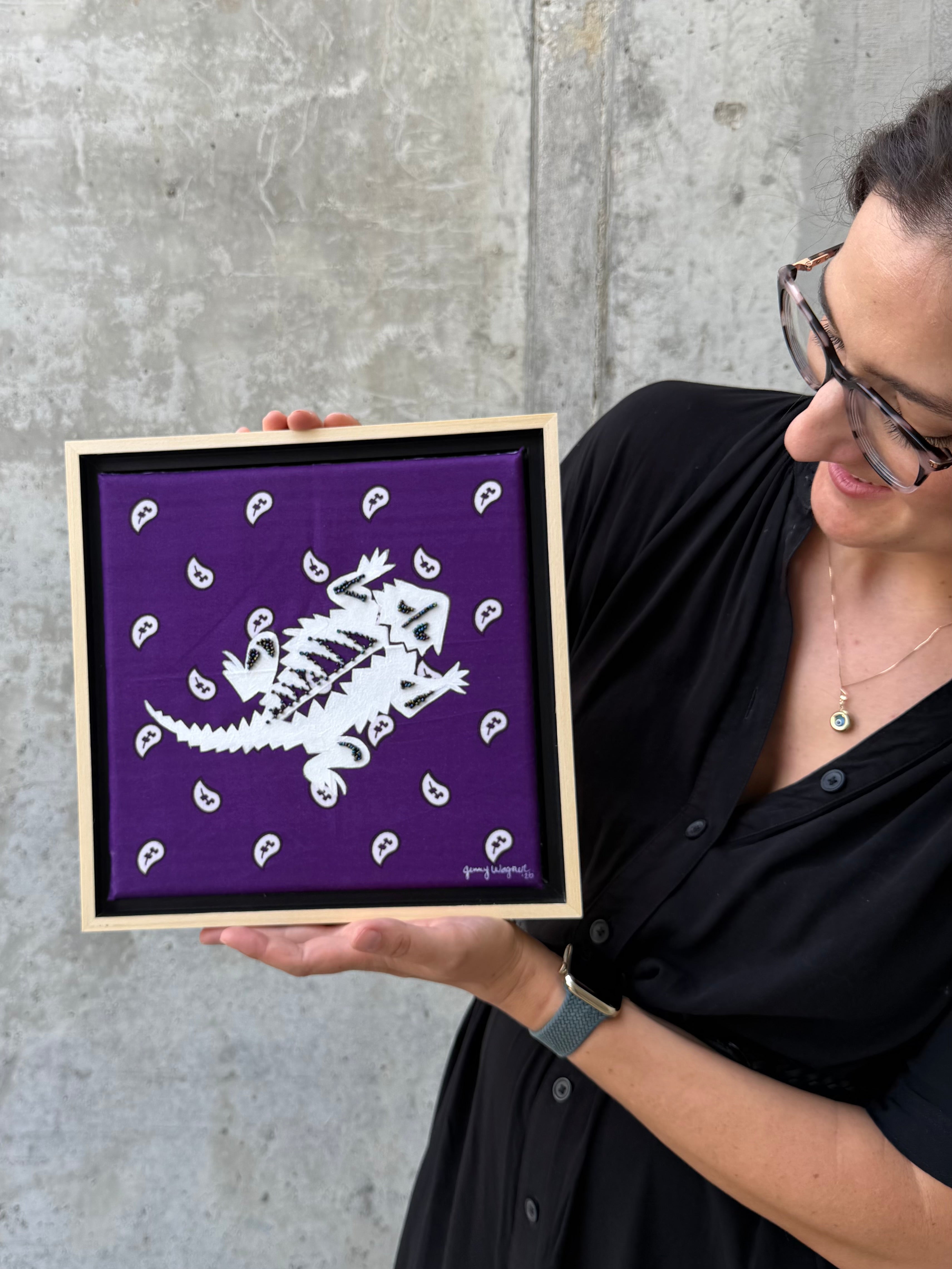 Side view of artist Jenny Wagner holding her 10x10 mixed media piece "Purple Reign" from her Bandana Series