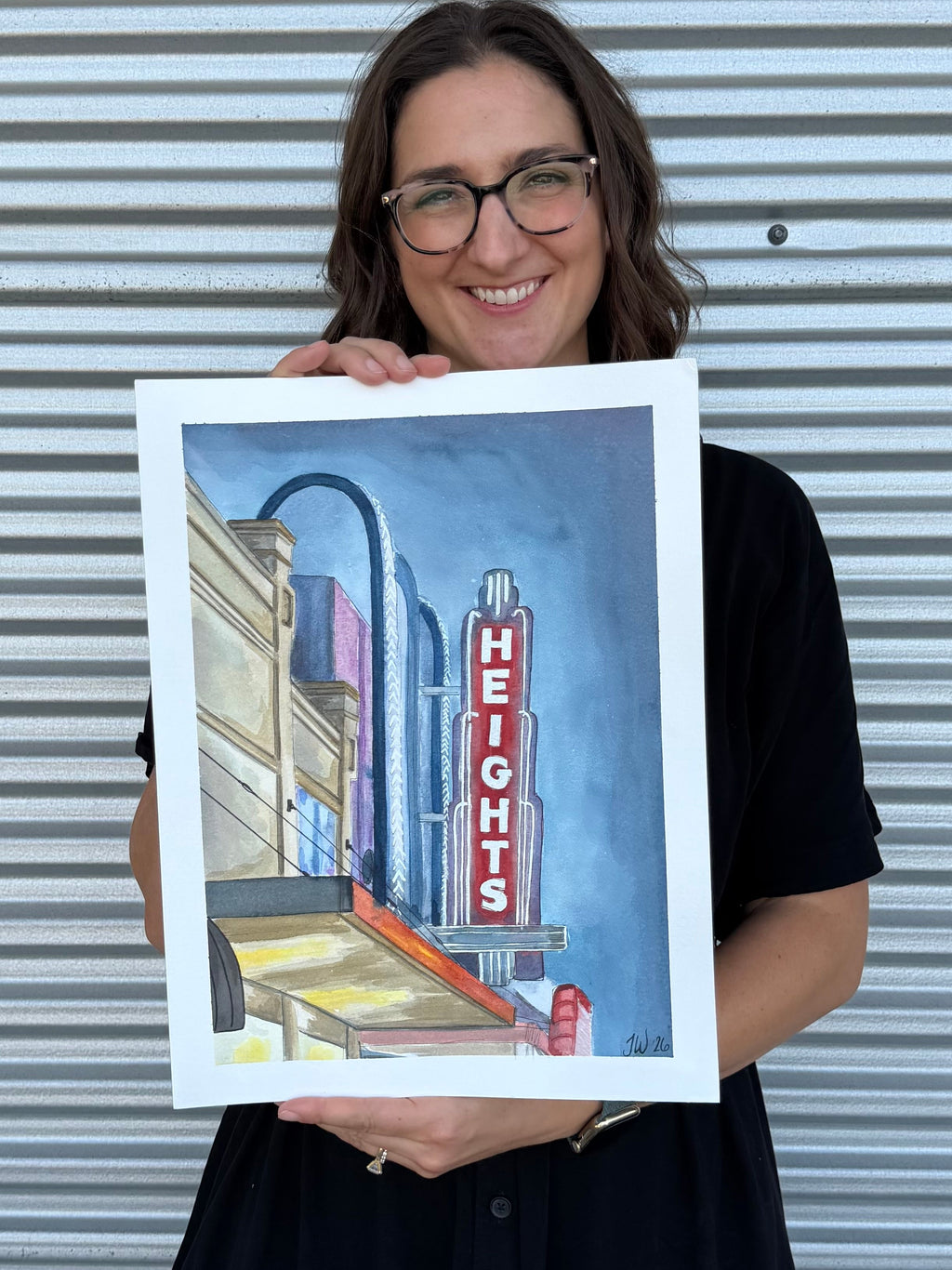 Jenny Wagner holding the original watercolor painting, "The Heights Theater" featuring Houston's iconic theater marquee