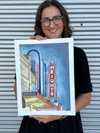 Jenny Wagner holding the original watercolor painting, "The Heights Theater" featuring Houston's iconic theater marquee