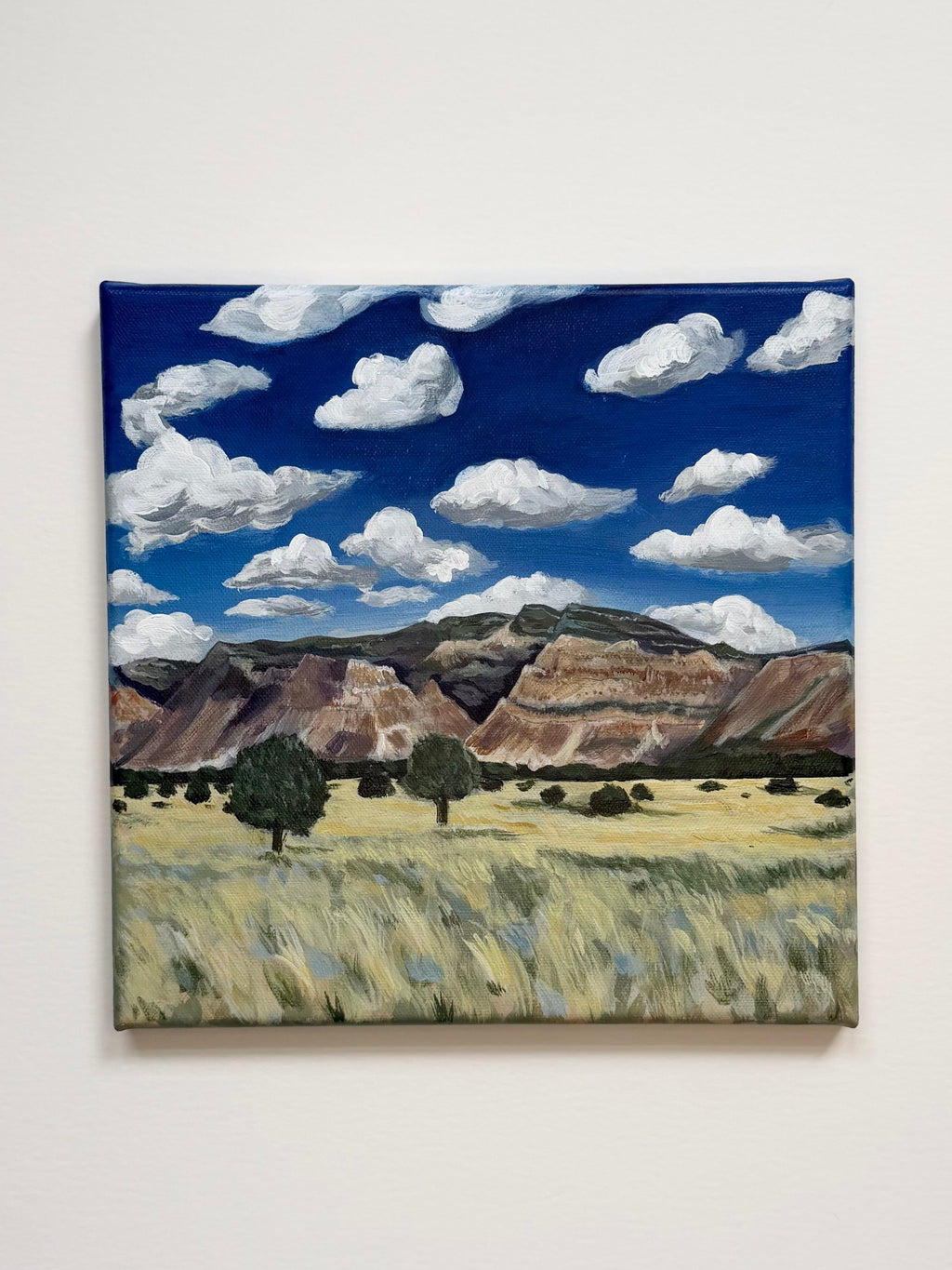Original acrylic landscape painting titled "Colorado to Utah" featuring colorful mountains beneath bright blue skies and white clouds.