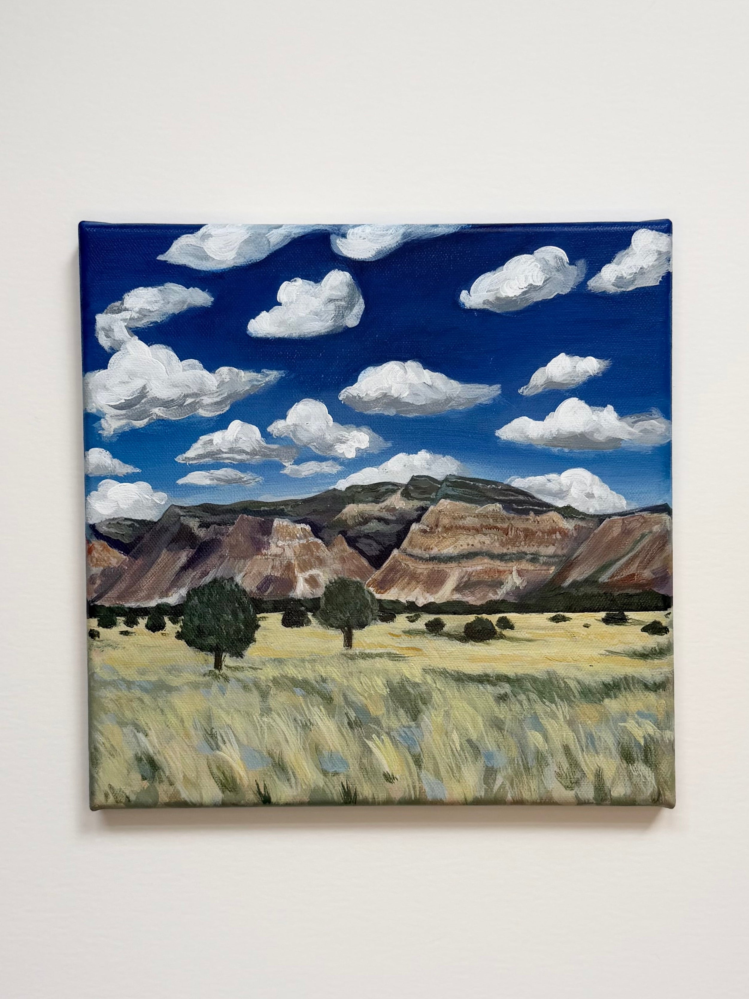 Original acrylic landscape painting titled "Colorado to Utah" featuring colorful mountains beneath bright blue skies and white clouds.