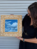 Texas artist, Jenny Wagner, with her oil painting Bandana Sky. This painting is done on a golden yellow hand stretched bandana with a deep blue sky with clouds.