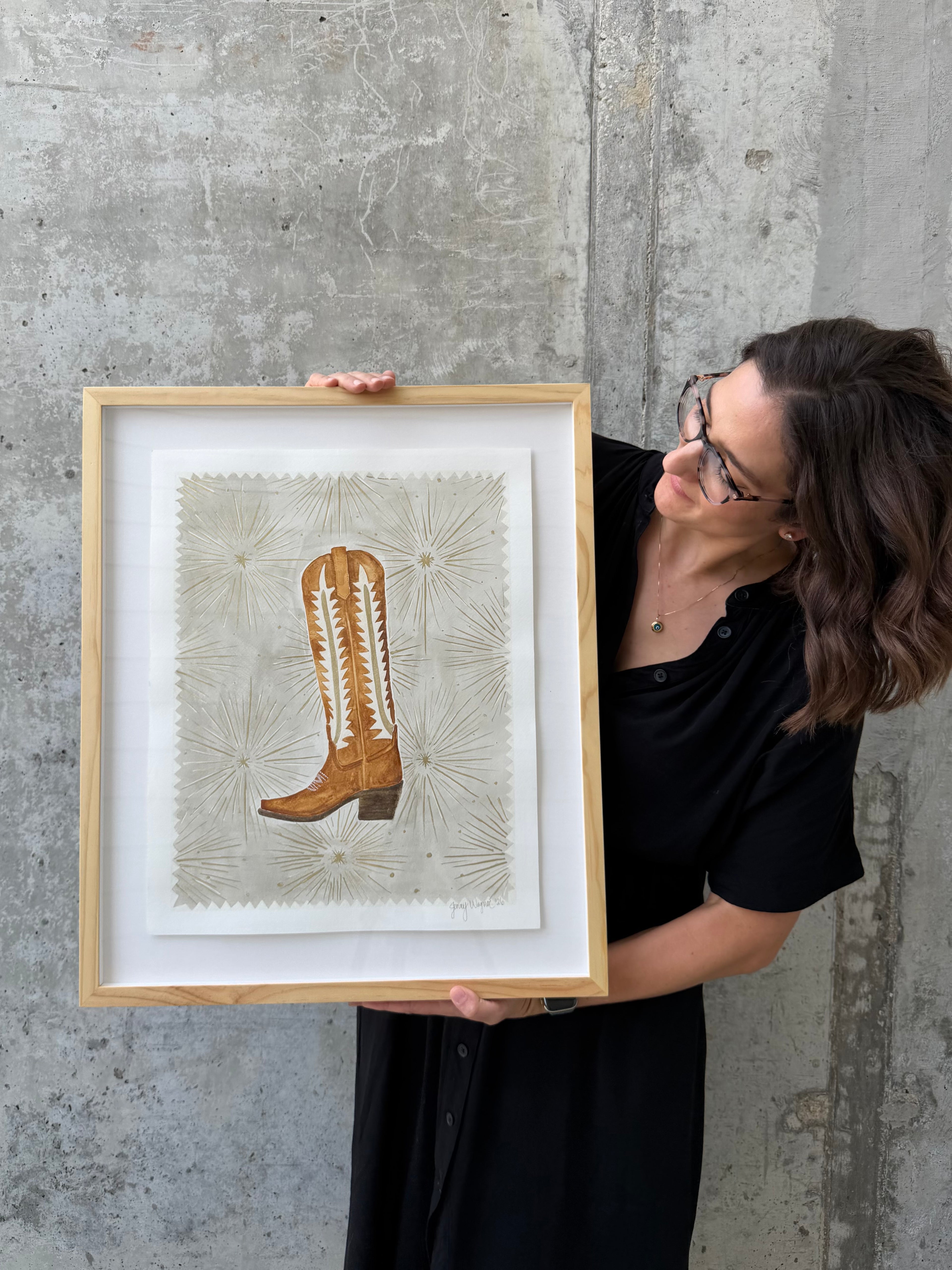 Side view of artist Jenny Wagner with her painting "Starburst Boot" a watercolor with metallic details.