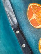 A close-up painting of a kitchen still life painting, Oranges on Blue, by Texas artist Jenny Wagner. The painting shows a kitchen knife with a black handle and silver blade, placed diagonally on a teal background with orange slice illustrations