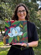 Artist Jenny Wagner with her original acrylic painting, "Magnolia in Pink" the painting depicts a single white magnolia bloom among colorful flowers with a magenta background