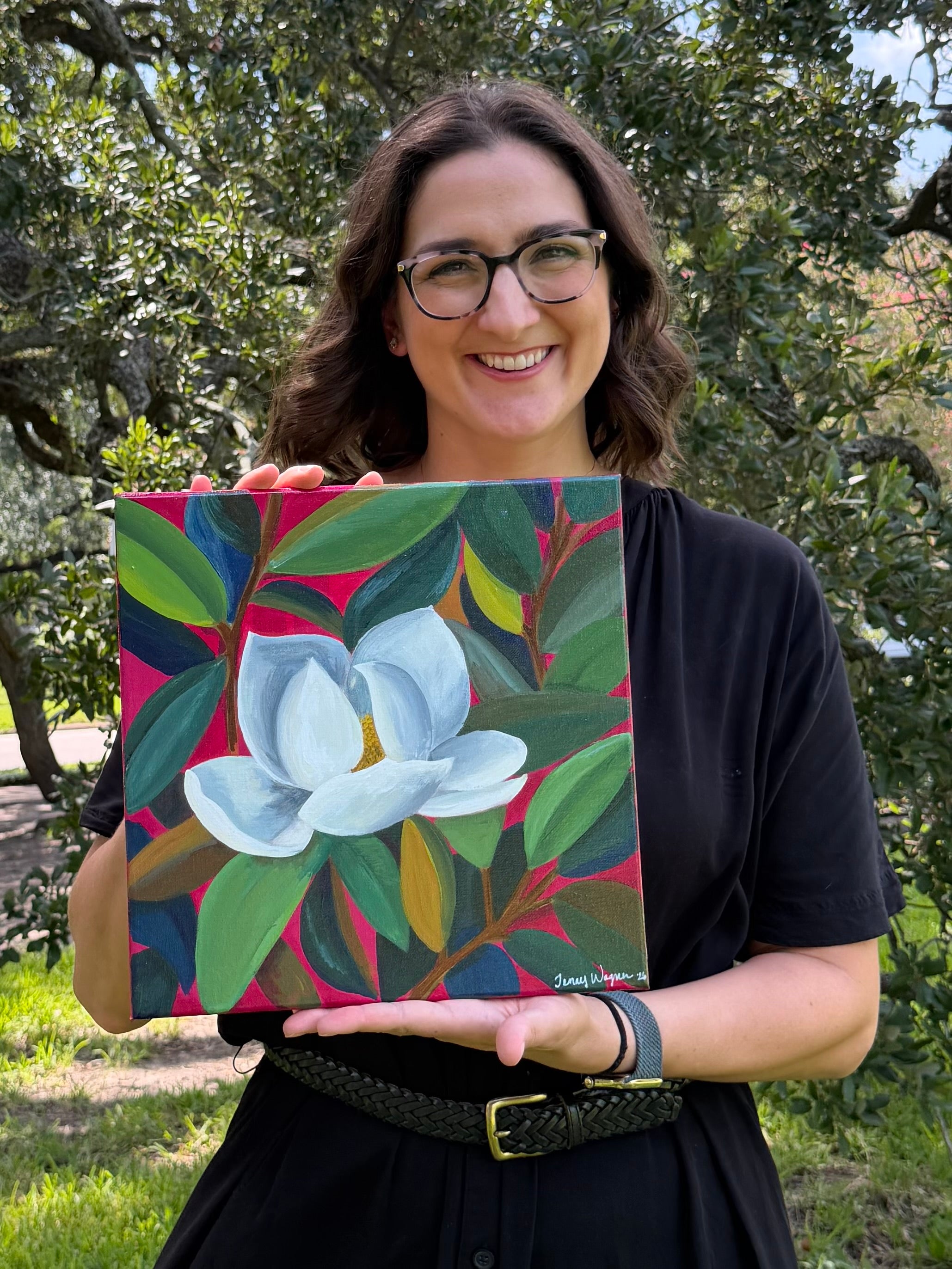 Artist Jenny Wagner with her original acrylic painting, "Magnolia in Pink" the painting depicts a single white magnolia bloom among colorful flowers with a magenta background