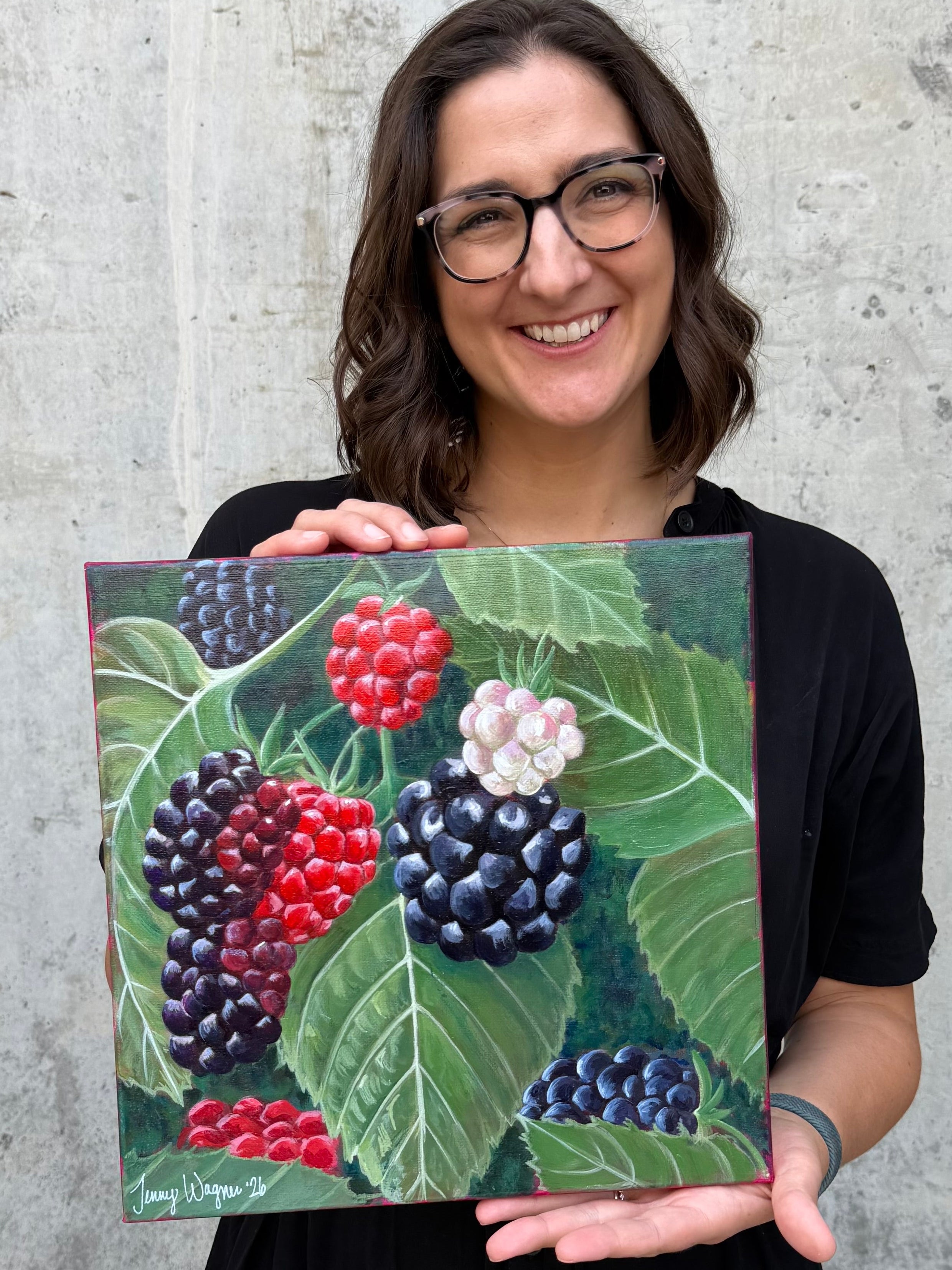 Jenny Wagner holding the original acrylic painting "Wild Blackberries" featuring ripe blackberry clusters and lush green leaves