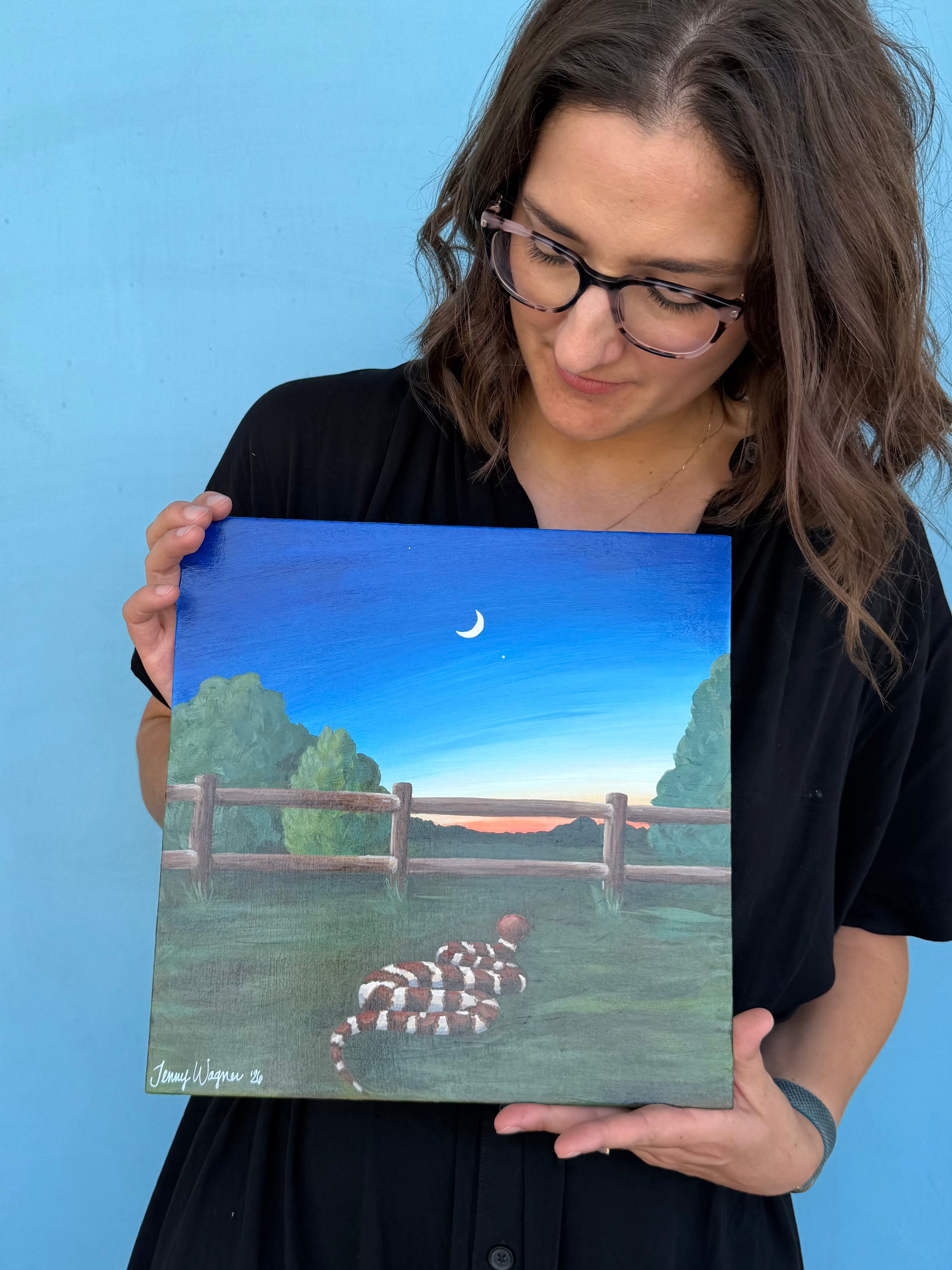 Texas artist Jenny Wagner displaying her original acrylic painting of a Texas sunset with a copperhead snake