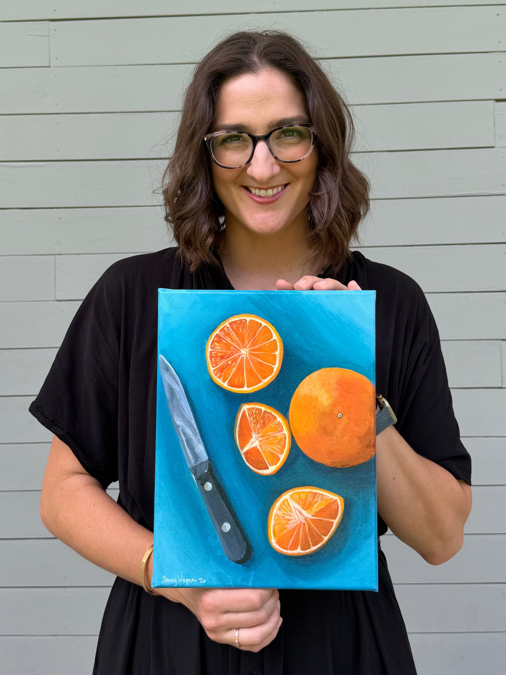 Texas artist Jenny Wagner shown holding her original acrylic painting "Oranges on Blue" 